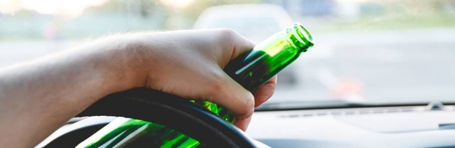 Man driving a car with a bottle of beer